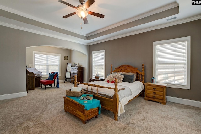 carpeted bedroom featuring ceiling fan, crown molding, and a tray ceiling