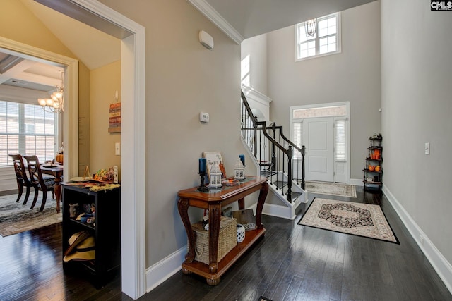 foyer entrance with dark wood-type flooring, a chandelier, and crown molding