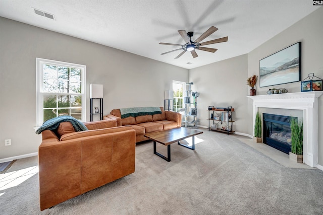 carpeted living room featuring ceiling fan and a textured ceiling