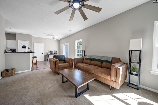 living area with baseboards, a ceiling fan, and light carpet