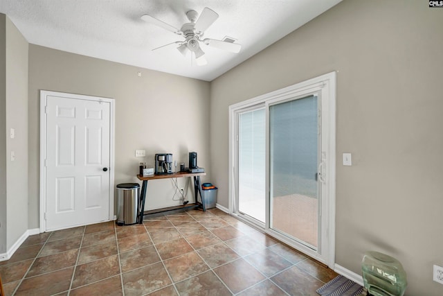 empty room with a textured ceiling, tile patterned flooring, and ceiling fan