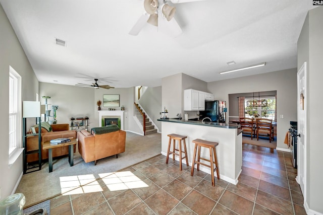 kitchen with kitchen peninsula, white cabinetry, black refrigerator, and ceiling fan