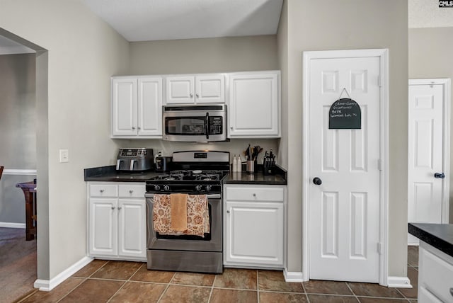 kitchen with baseboards, white cabinetry, appliances with stainless steel finishes, and dark countertops