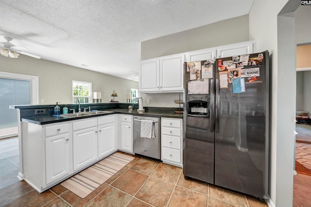 kitchen with kitchen peninsula, white cabinets, appliances with stainless steel finishes, a textured ceiling, and sink