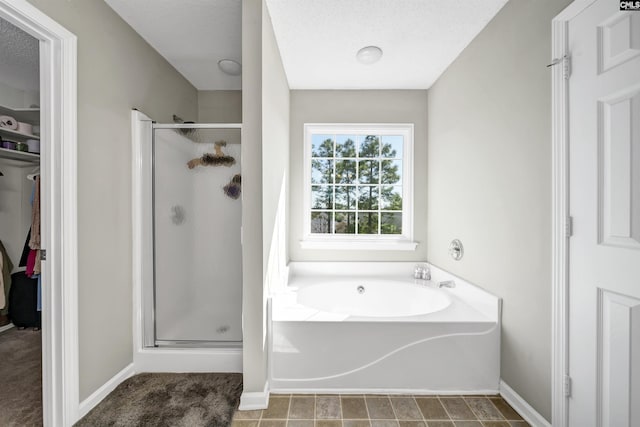 full bathroom with baseboards, a stall shower, a garden tub, and a spacious closet