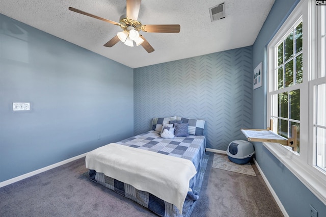 bedroom with a textured ceiling, carpet, a ceiling fan, baseboards, and visible vents