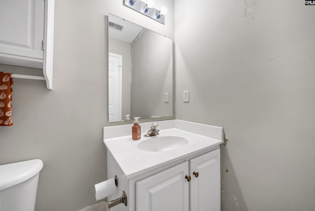 half bath featuring toilet, visible vents, and vanity