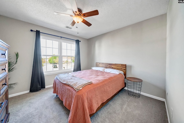 carpeted bedroom featuring ceiling fan and a textured ceiling