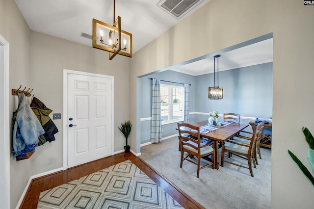 dining space featuring baseboards, visible vents, wood finished floors, and a notable chandelier