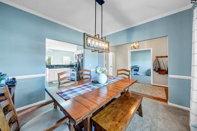 carpeted dining area with ornamental molding and sink