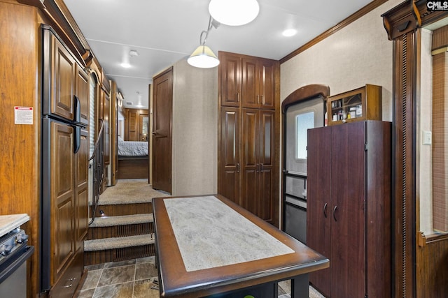 kitchen with fridge, stainless steel range oven, dark tile patterned flooring, crown molding, and paneled built in fridge