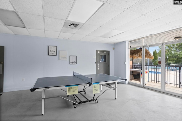 game room featuring a paneled ceiling and concrete floors