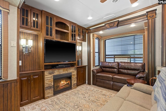 living room featuring ceiling fan, wood walls, and a fireplace