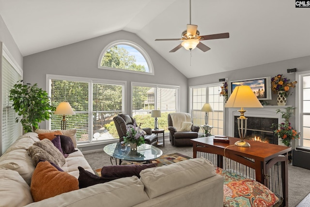 carpeted living room with ceiling fan, high vaulted ceiling, a tile fireplace, and plenty of natural light