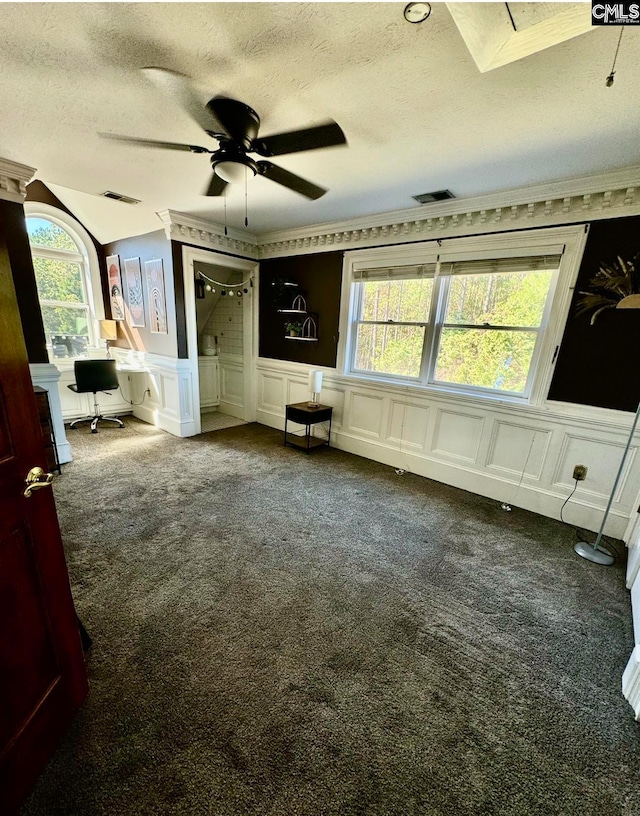 unfurnished bedroom featuring crown molding, a textured ceiling, multiple windows, and dark carpet