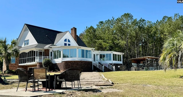 rear view of property with a patio area, a yard, and a sunroom