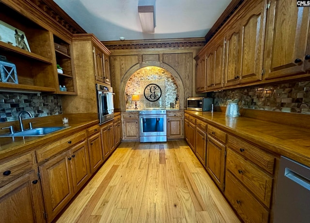 kitchen featuring appliances with stainless steel finishes, sink, backsplash, wood counters, and light hardwood / wood-style flooring