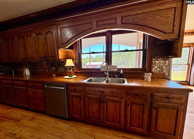 kitchen with dishwasher, ornamental molding, sink, a textured ceiling, and light hardwood / wood-style floors