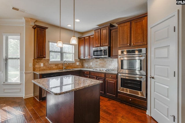 kitchen with a kitchen island, stainless steel appliances, sink, pendant lighting, and dark hardwood / wood-style flooring