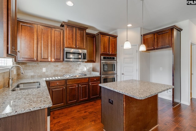 kitchen featuring a kitchen island, dark hardwood / wood-style floors, stainless steel appliances, sink, and pendant lighting