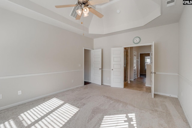 unfurnished bedroom with light colored carpet, a tray ceiling, and ceiling fan