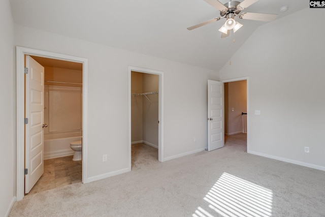 unfurnished bedroom with ceiling fan, connected bathroom, a closet, a walk in closet, and light colored carpet