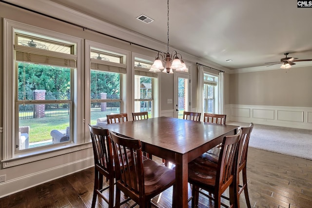 dining space featuring dark hardwood / wood-style flooring, ornamental molding, ceiling fan with notable chandelier, and plenty of natural light