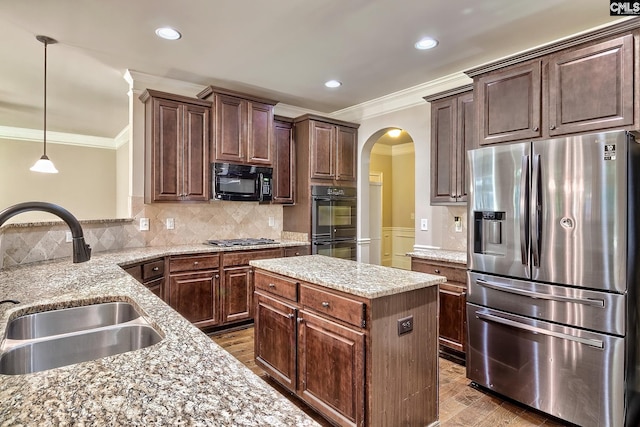 kitchen with a kitchen island, hardwood / wood-style flooring, black appliances, pendant lighting, and sink