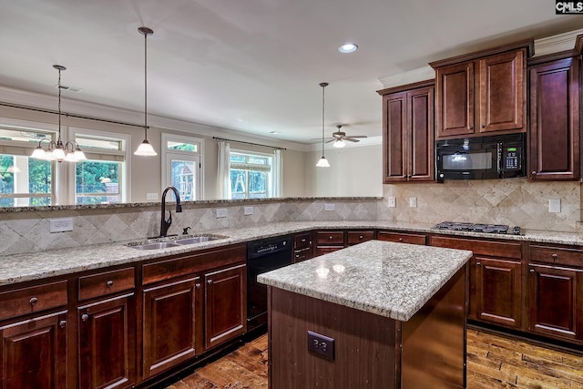 kitchen with dark wood-type flooring, black appliances, sink, and a kitchen island