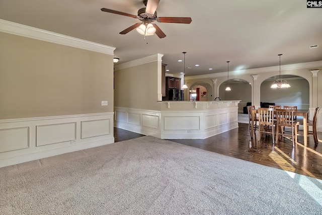 interior space with ceiling fan with notable chandelier, ornamental molding, and dark hardwood / wood-style floors