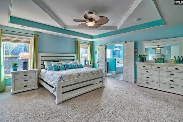 bedroom with connected bathroom, a raised ceiling, multiple windows, and light colored carpet