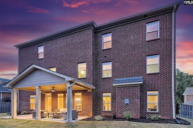 back house at dusk featuring a patio area and an outdoor hangout area