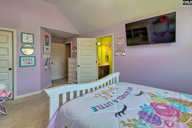 carpeted bedroom with ensuite bathroom and vaulted ceiling