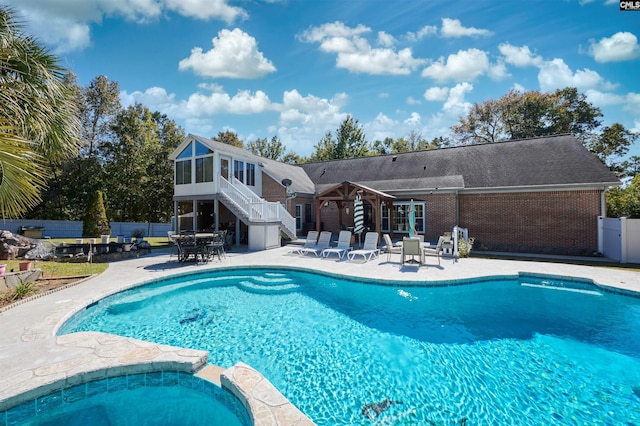 view of pool featuring a patio, an in ground hot tub, and a sunroom