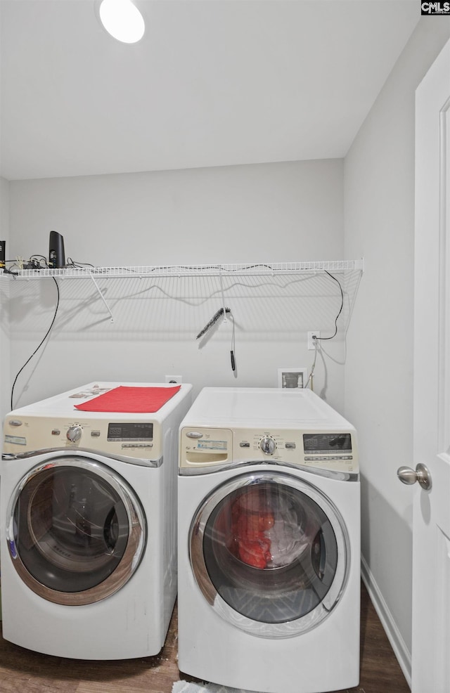 clothes washing area with dark hardwood / wood-style floors and washing machine and clothes dryer