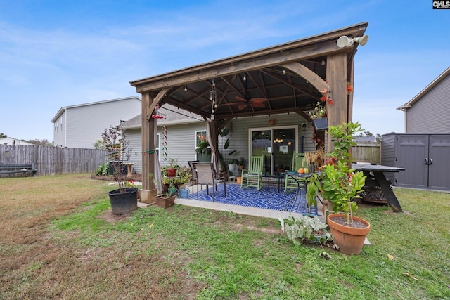 rear view of property featuring a shed, a gazebo, a lawn, and ceiling fan