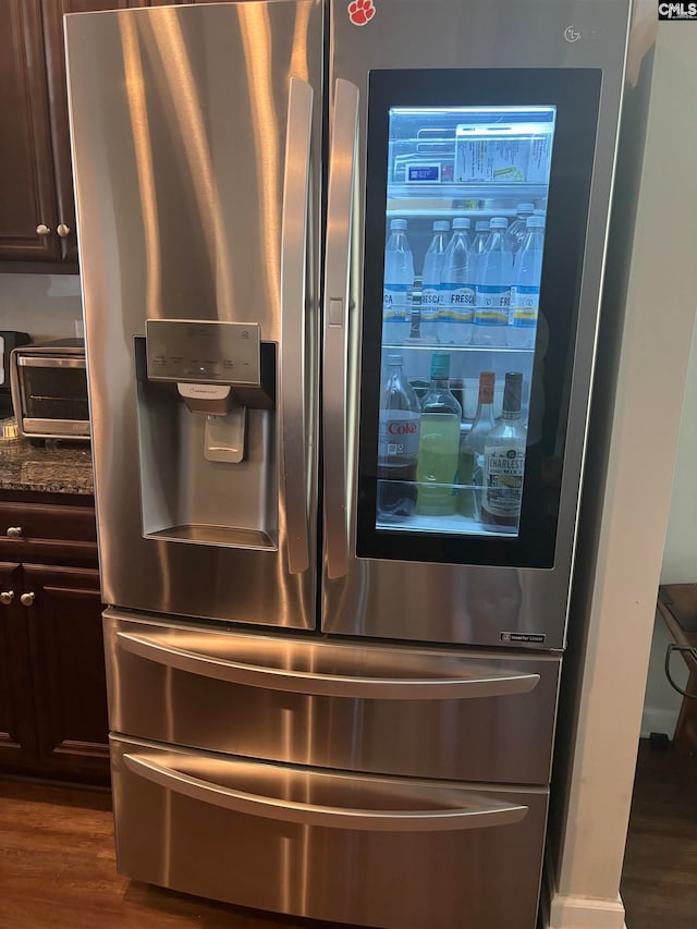 details featuring dark brown cabinetry, stainless steel refrigerator with ice dispenser, dark stone countertops, and dark hardwood / wood-style floors