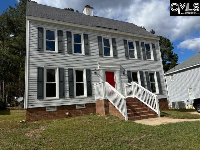 colonial-style house featuring a front yard and central AC