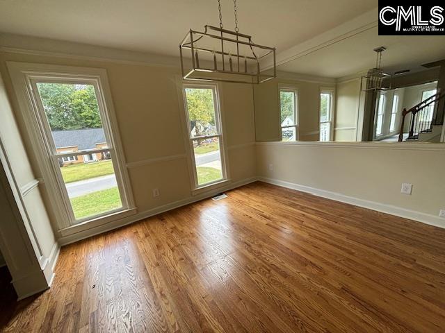 unfurnished dining area featuring a notable chandelier, hardwood / wood-style floors, and a wealth of natural light