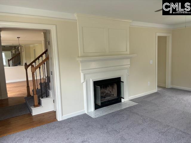 unfurnished living room featuring an inviting chandelier, crown molding, and carpet