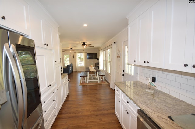 kitchen featuring light stone countertops, appliances with stainless steel finishes, backsplash, white cabinets, and dark wood-type flooring