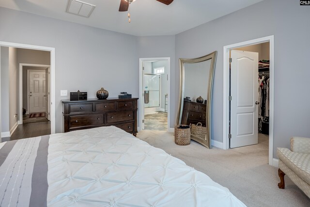 carpeted bedroom featuring a closet, a spacious closet, ensuite bath, and ceiling fan