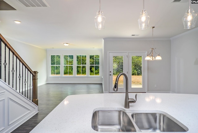 kitchen with light stone countertops, ornamental molding, dark hardwood / wood-style floors, pendant lighting, and sink