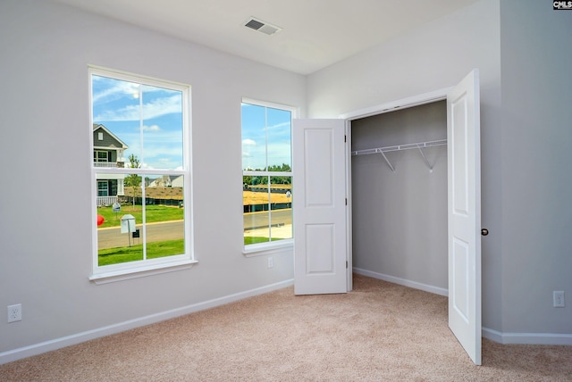 unfurnished bedroom with light colored carpet and a closet