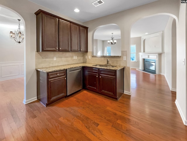 kitchen with wood-type flooring, sink, dishwasher, decorative light fixtures, and an inviting chandelier