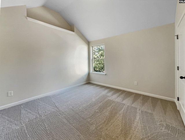 carpeted empty room with vaulted ceiling