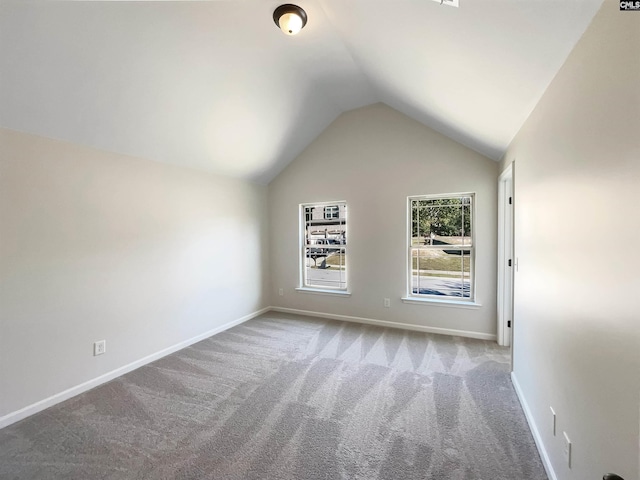 carpeted empty room featuring vaulted ceiling