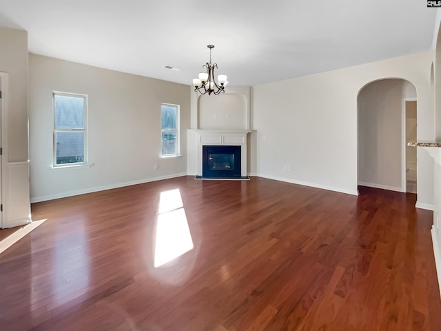 unfurnished living room featuring a notable chandelier and dark hardwood / wood-style floors