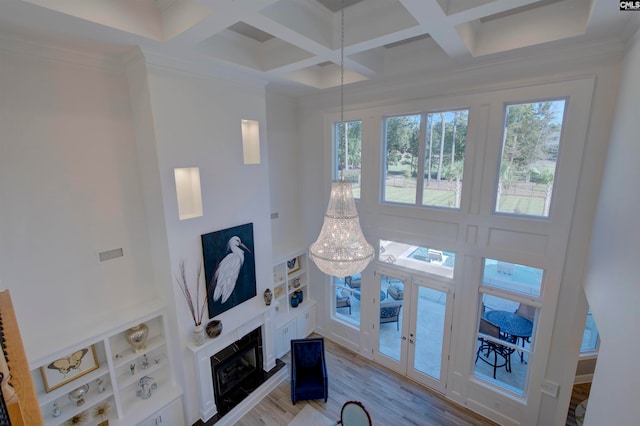 living room featuring crown molding, light hardwood / wood-style floors, coffered ceiling, beam ceiling, and a notable chandelier