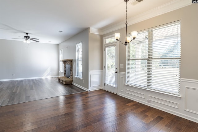 interior space featuring ornamental molding, a stone fireplace, dark hardwood / wood-style floors, and ceiling fan with notable chandelier